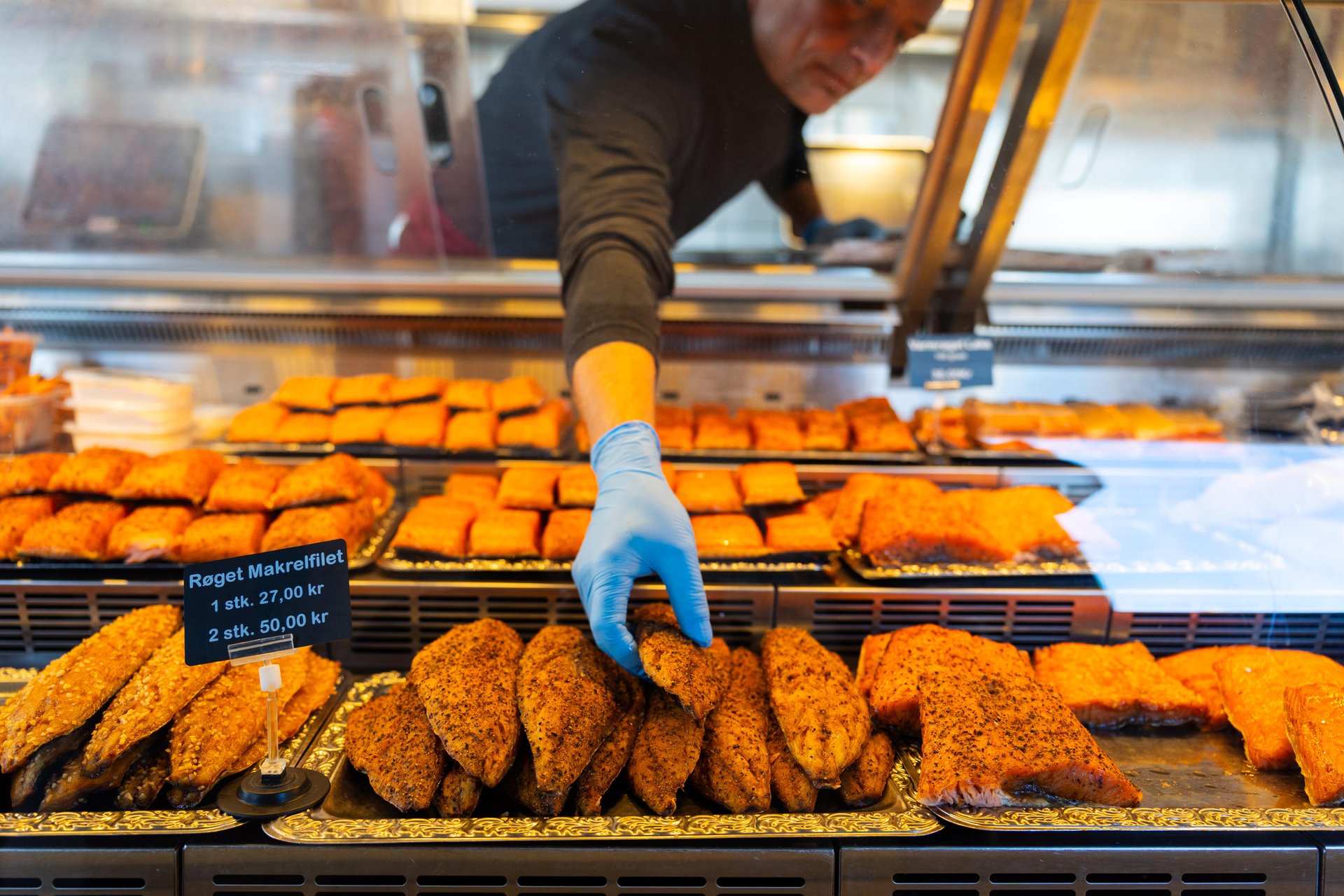 Fish counter in Copenhagen market with hand reaching for prepared food, used as the Taste Copenhagen hero cover image.